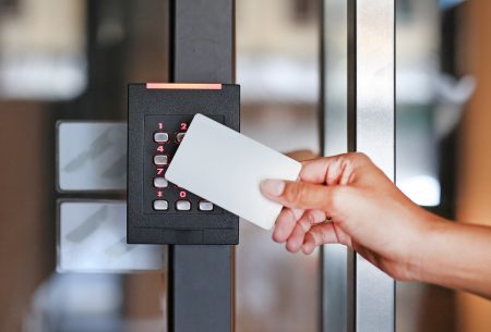 Door access control - young woman holding a key card to lock and unlock door.